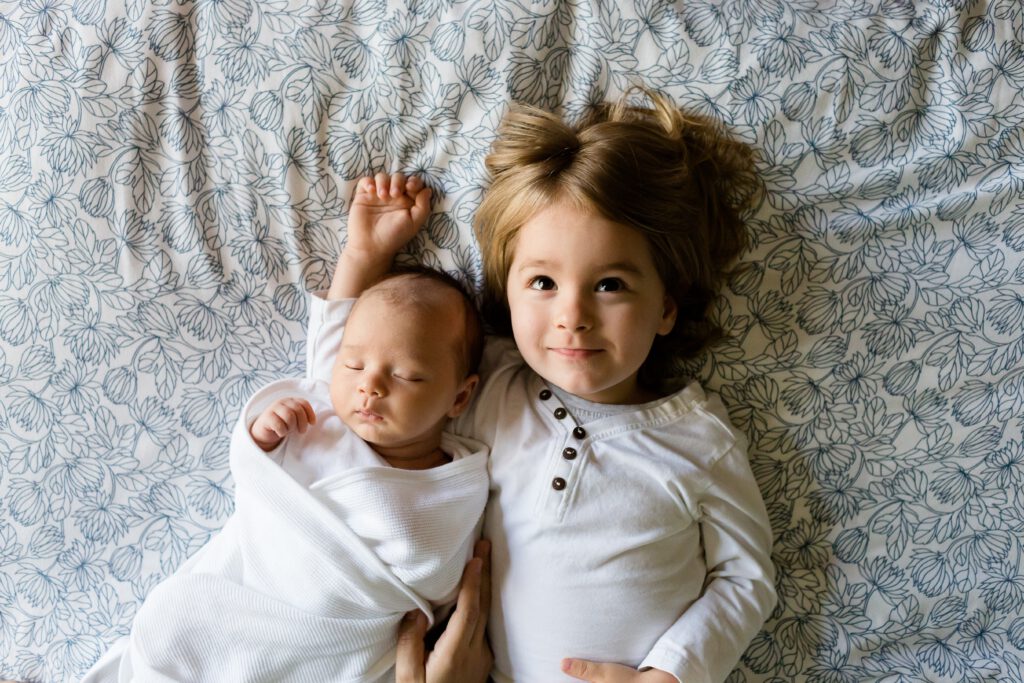 Ein Baby und ein Kleinkind liegen nebeneinander im Bett